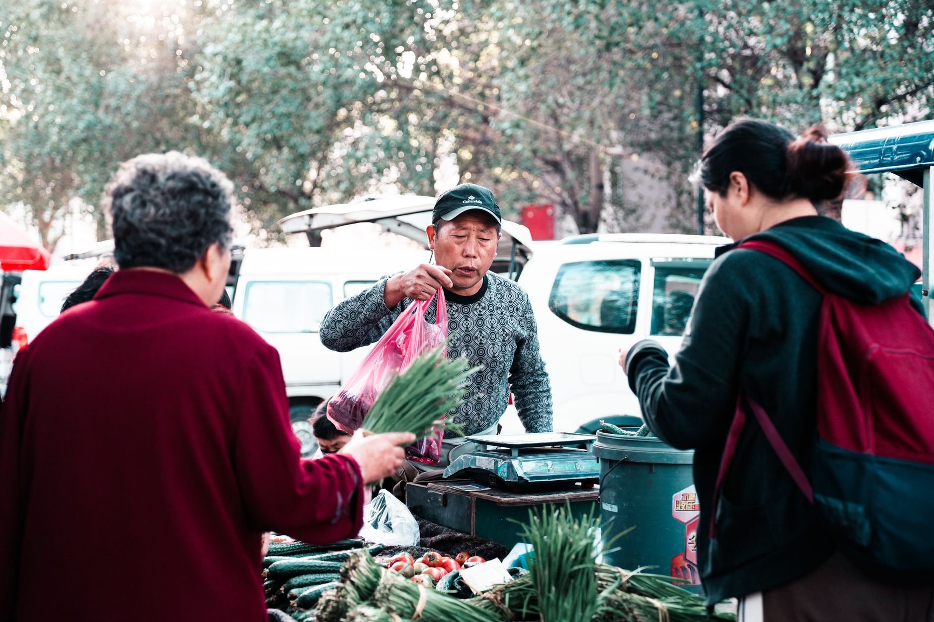 Vendors and neighbors exchanging fresh produce at an outdoor community market