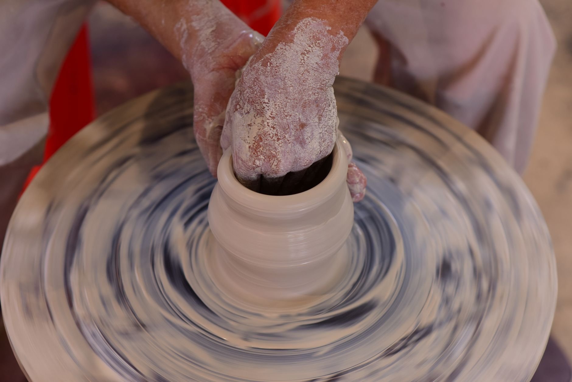 Hands shaping clay on a pottery wheel in a studio