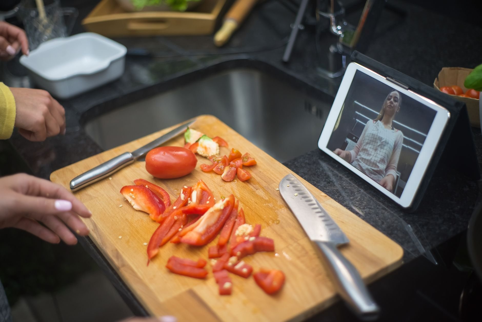 Hands preparing fresh vegetables on a chopping board in a community kitchen